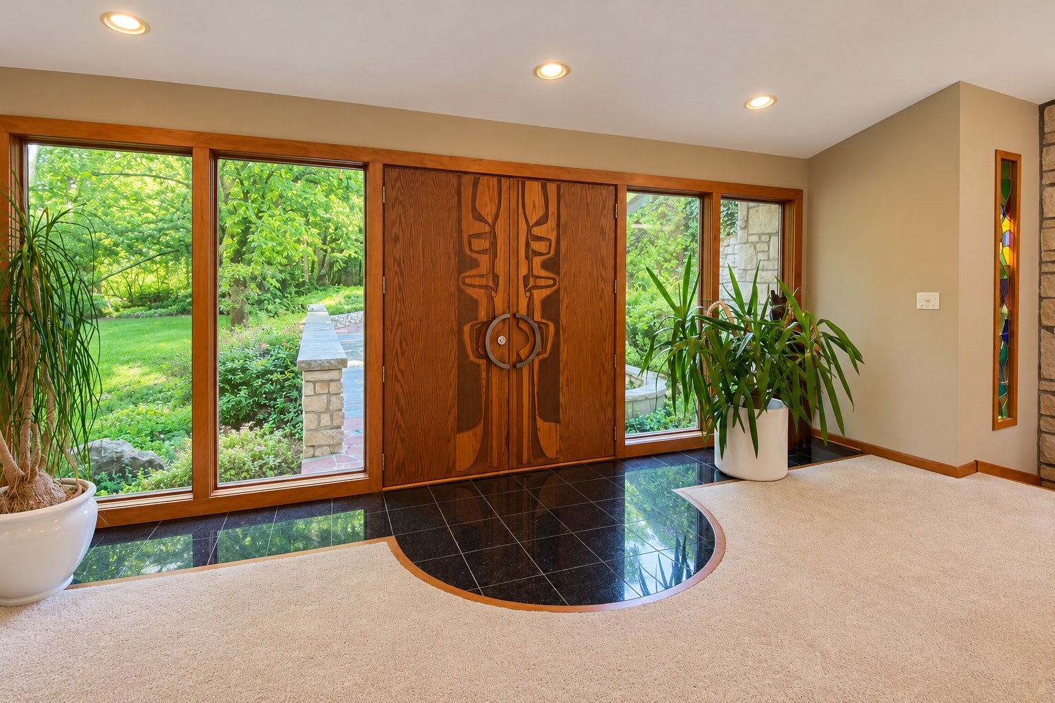 Before remodeling: carpeted foyer with custom wood double doors and garden views