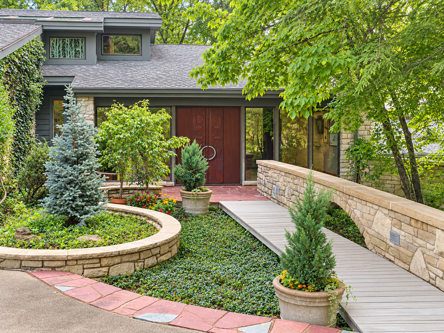 Before: original landscaped front entrance with stone walls and mature plantings